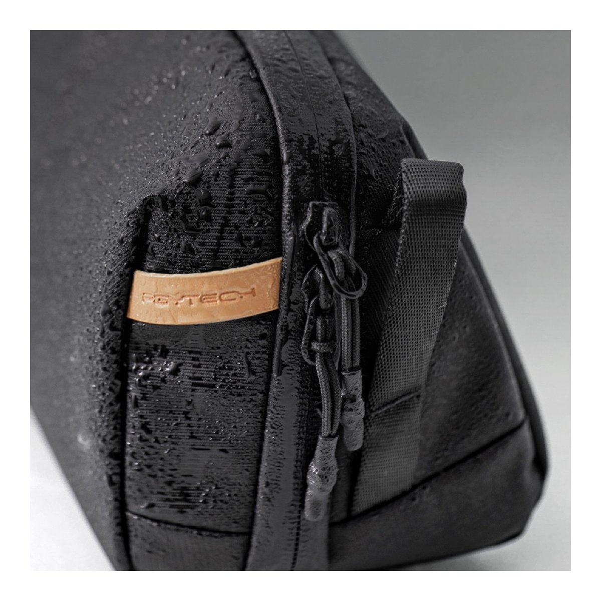 PGYTECH Wash Pouch(Twilight Black) - Detailansicht: Wasserdichte Oberfläche der schwarzen Tasche mit Wassertropfen, Reißverschluss und PGYTECH-Logo.