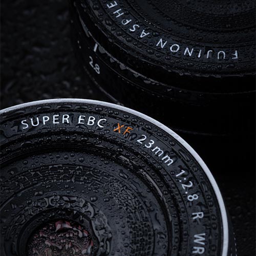 Detailaufnahme des spritzwassergeschützten FUJINON XF23mmF2.8 R WR Objektivs mit Wassertropfen