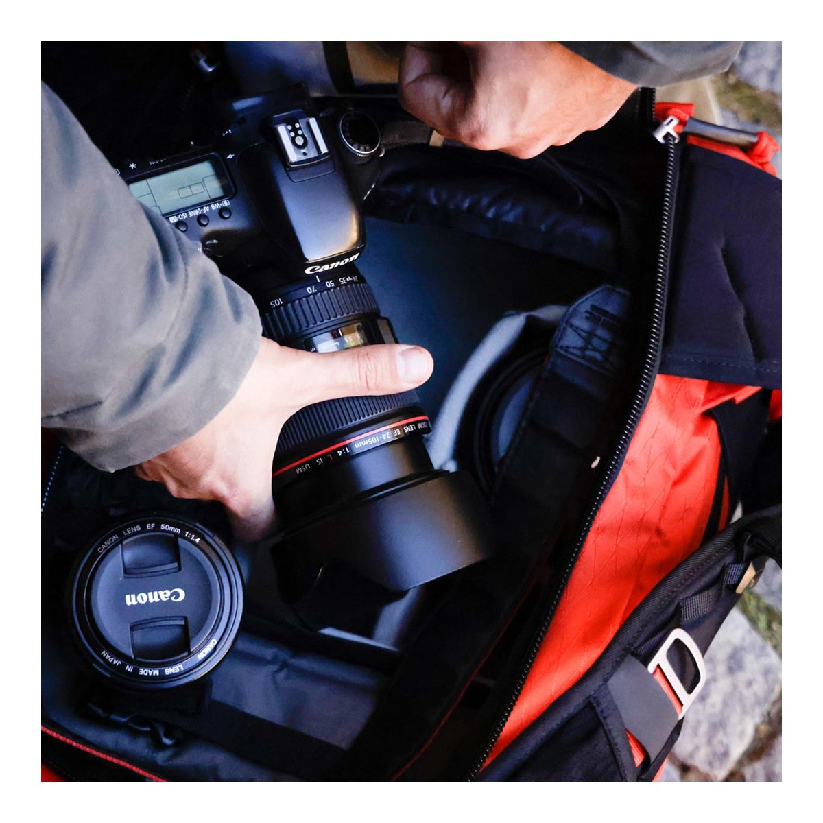 F-Stop DuraDiamond Ajna - Magma - Anwendungsbeispiel: Hände verstauen Kamera und Objektiv in einem Fotorucksack.