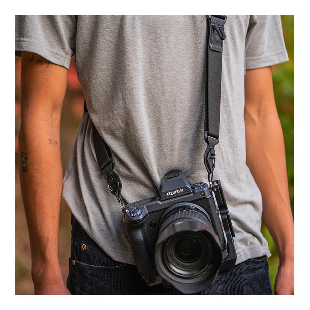 WANDRD Sling Strap - Anwendungsbeispiel: Schwarzer Kameragurt mit Kamera von Person getragen.