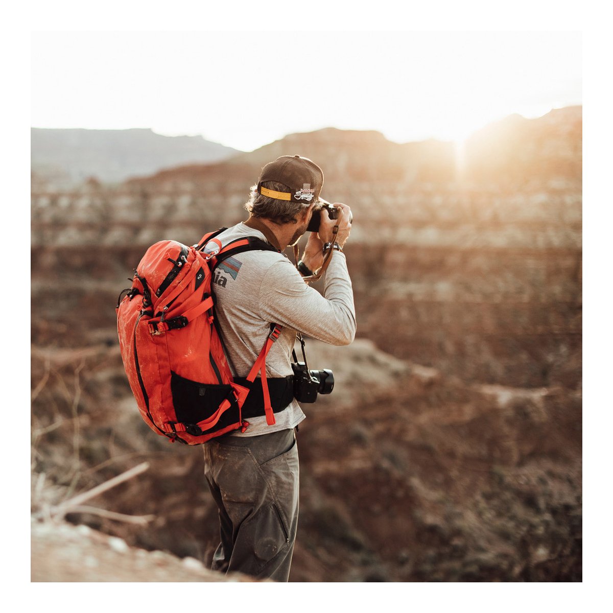 F-Stop DuraDiamond Ajna - Magma - Anwendungsbeispiel: Rückansicht einer Person mit rotem Outdoor-Rucksack beim Fotografieren.