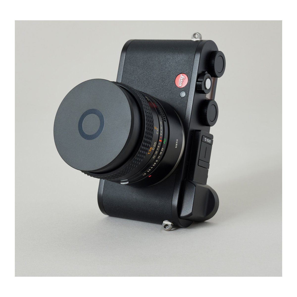 Urth 43mm Objektivfilterkappen - Schräge Frontansicht einer schwarzen Leica Kamera mit angesetztem Objektiv und Deckel.