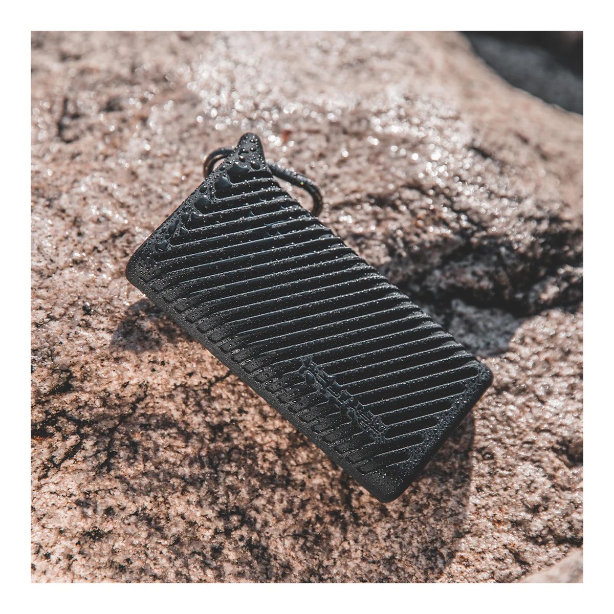 PGYTECH CFexpress CreateMate Card Reader Case Type B/SD (Classic Black) - Anwendungsbeispiel des schwarzen Produkts auf nassem Felsen, bedeckt mit Wassertropfen.