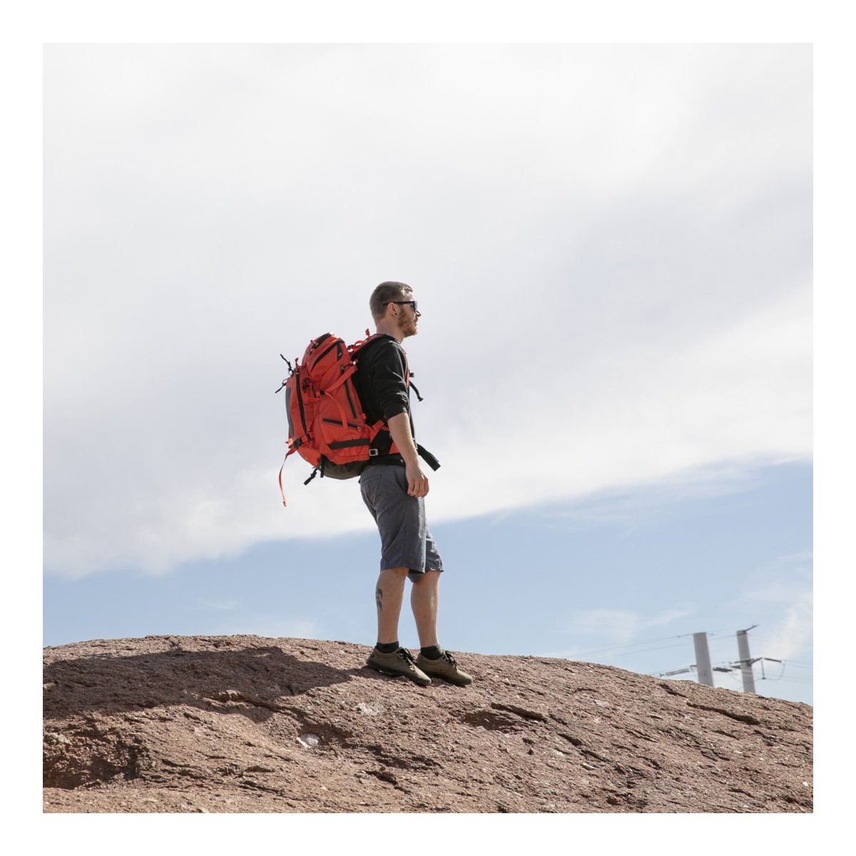 F-Stop DuraDiamond Tilopa Bundle - Magma - Anwendungsbeispiel: Mann mit rotem Trekkingrucksack auf Felsen, Seitenansicht.