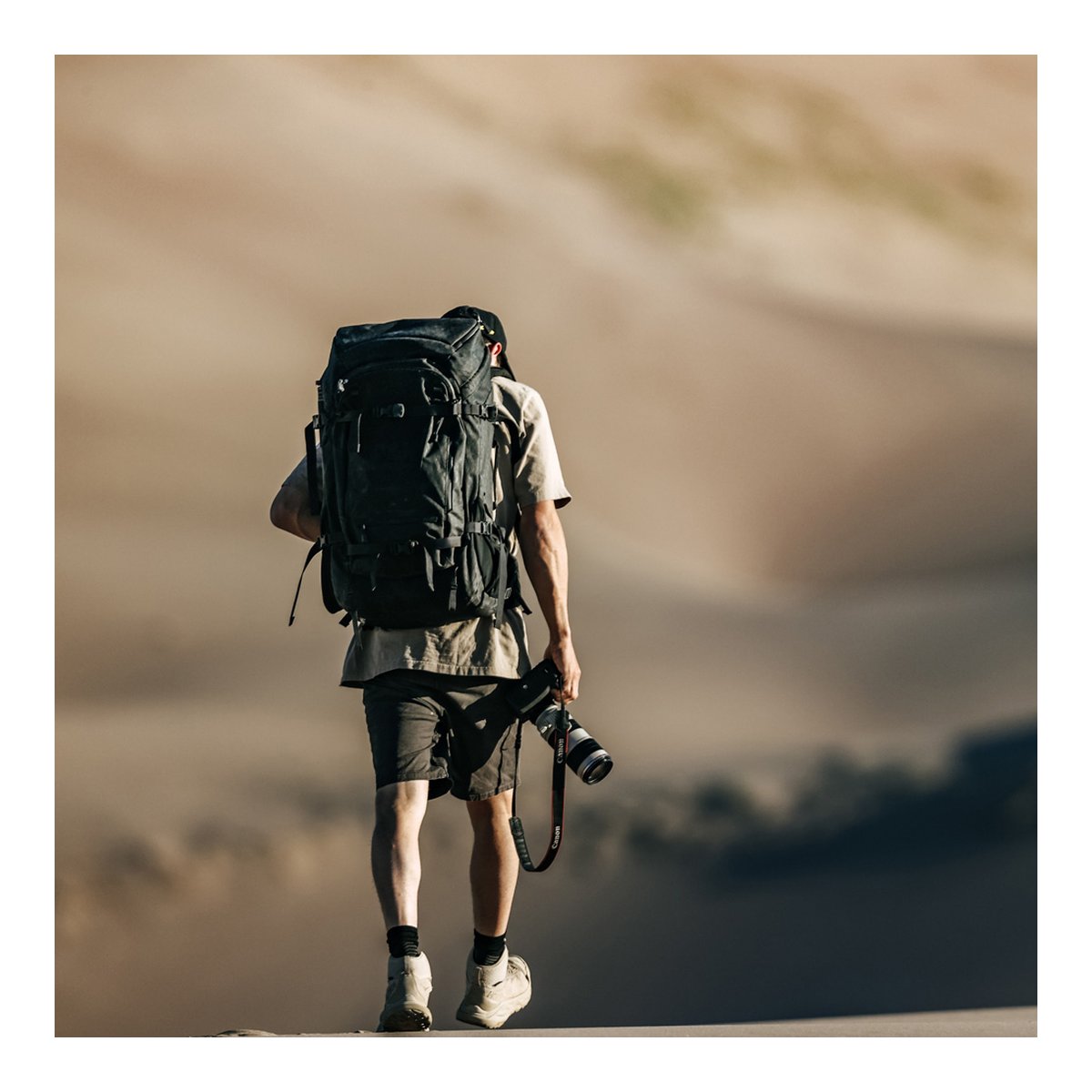 F-Stop DuraDiamond Shinn - Anthrazit - Anwendungsbeispiel: Rückansicht eines Wanderers mit dem Rucksack und Kamera in den Sanddünen. F-Stop DuraDiamond Shinn - Anthrazit - Anwendungsbeispiel: Rückansicht eines Wanderers mit dem Rucksack und Kamera in den Sanddünen.