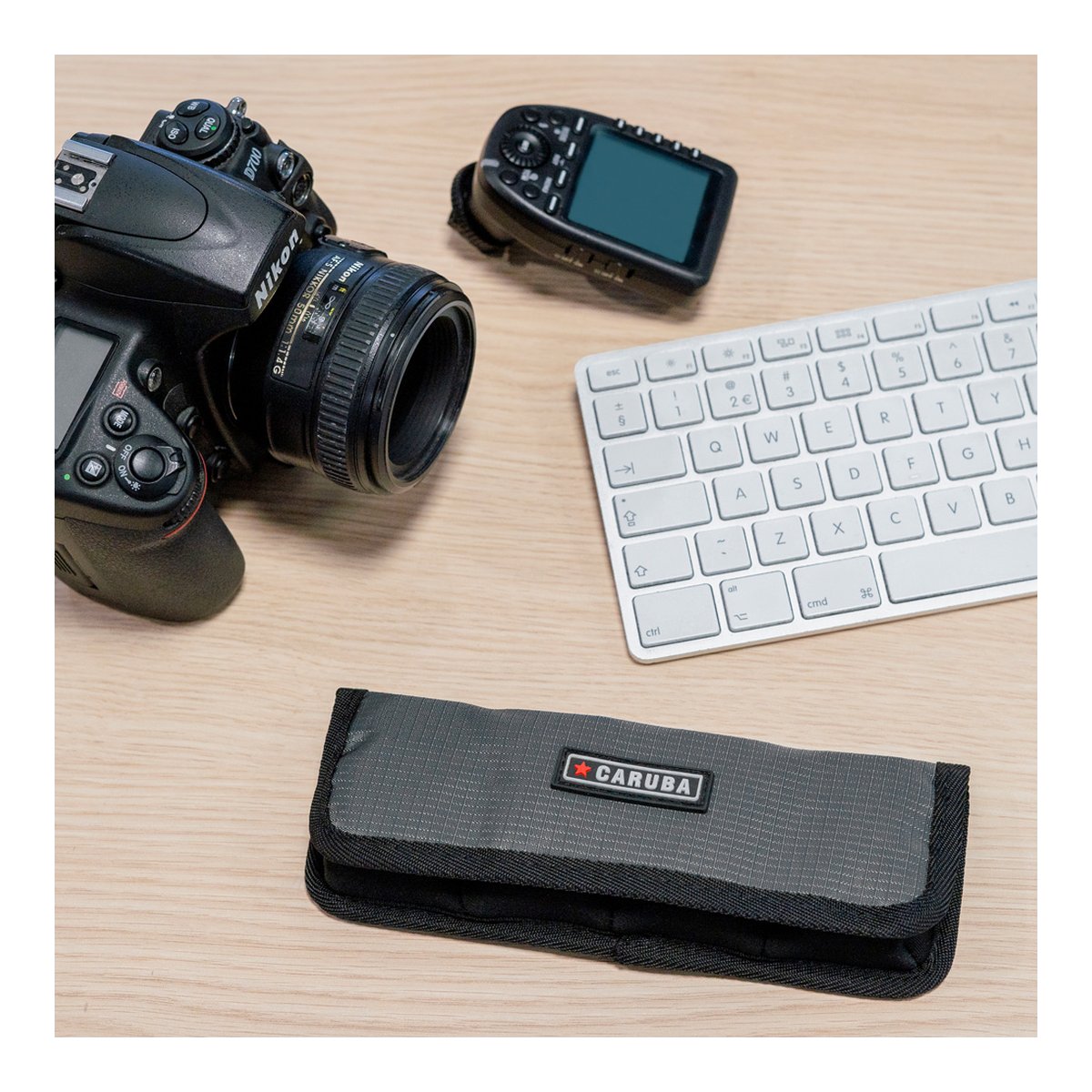 Caruba Batteriehalter Pro 4 Stück Grau - Anwendungsbeispiel: Graues Caruba Etui auf Schreibtisch neben Kamera und Tastatur.