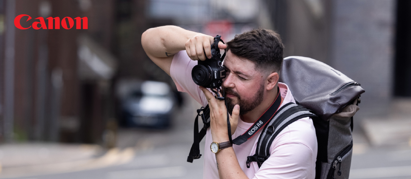 Canon EOS R8 Kombirabatt – 500 € sparen beim Kamerakauf Mann fotografiert mit Canon EOS R8 in urbaner Umgebung, Canon Logo oben links.