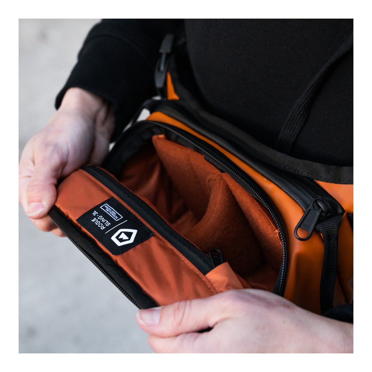 WANDRD ROGUE Sling 3L Sedona Orange - Detailansicht des geöffneten Hauptfachs einer orangefarbenen Tasche mit Label und Innenfutter. WANDRD ROGUE Sling 3L Sedona Orange - Detailansicht des geöffneten Hauptfachs einer orangefarbenen Tasche mit Label und Innenfutter.