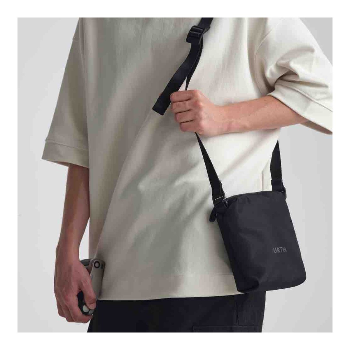 Urth Andesite Camera Pouch (Black) - Anwendungsbeispiel: Schwarze Urth-Tasche wird von einer Person crossbody getragen. Urth Andesite Camera Pouch (Black) - Anwendungsbeispiel: Schwarze Urth-Tasche wird von einer Person crossbody getragen.