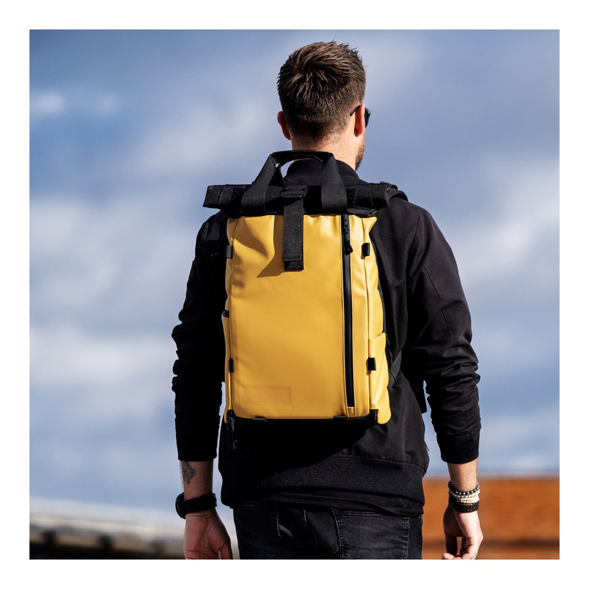 WANDRD PRVKE Lite 11-Liter Dallol Yellow - Anwendungsbeispiel: Gelber Roll-Top-Rucksack am Rücken eines Mannes, Rückansicht.