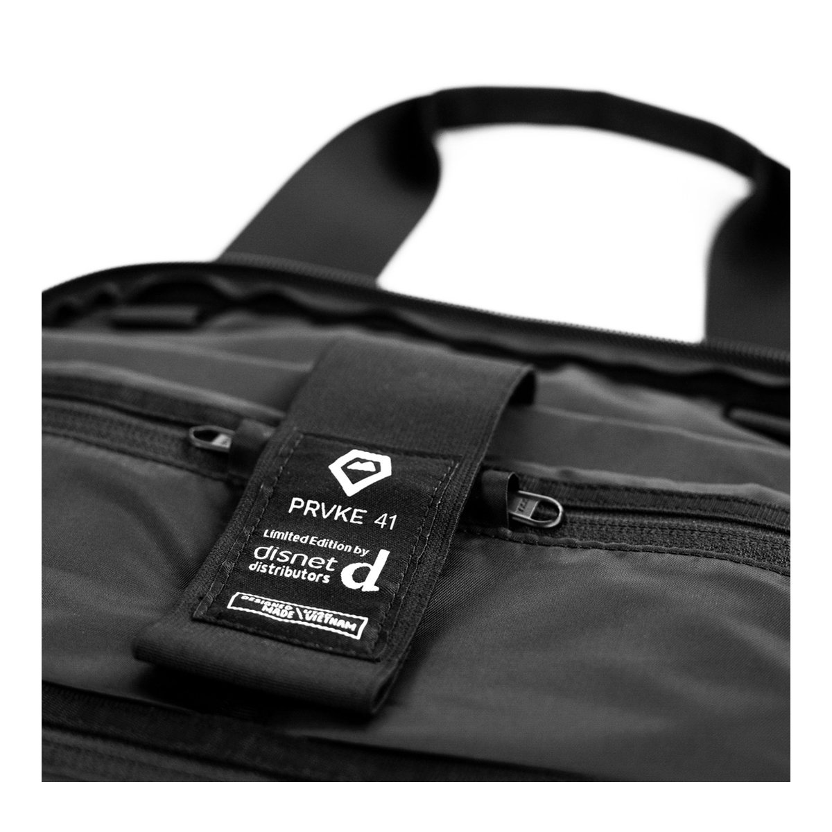 WANDRD PRVKE 41-Liter DisNet Grey Photo Bundel V3 - Detailansicht des PRVKE 41 Markenlabels auf schwarzer Tasche WANDRD PRVKE 41-Liter DisNet Grey Photo Bundel V3 - Detailansicht des PRVKE 41 Markenlabels auf schwarzer Tasche