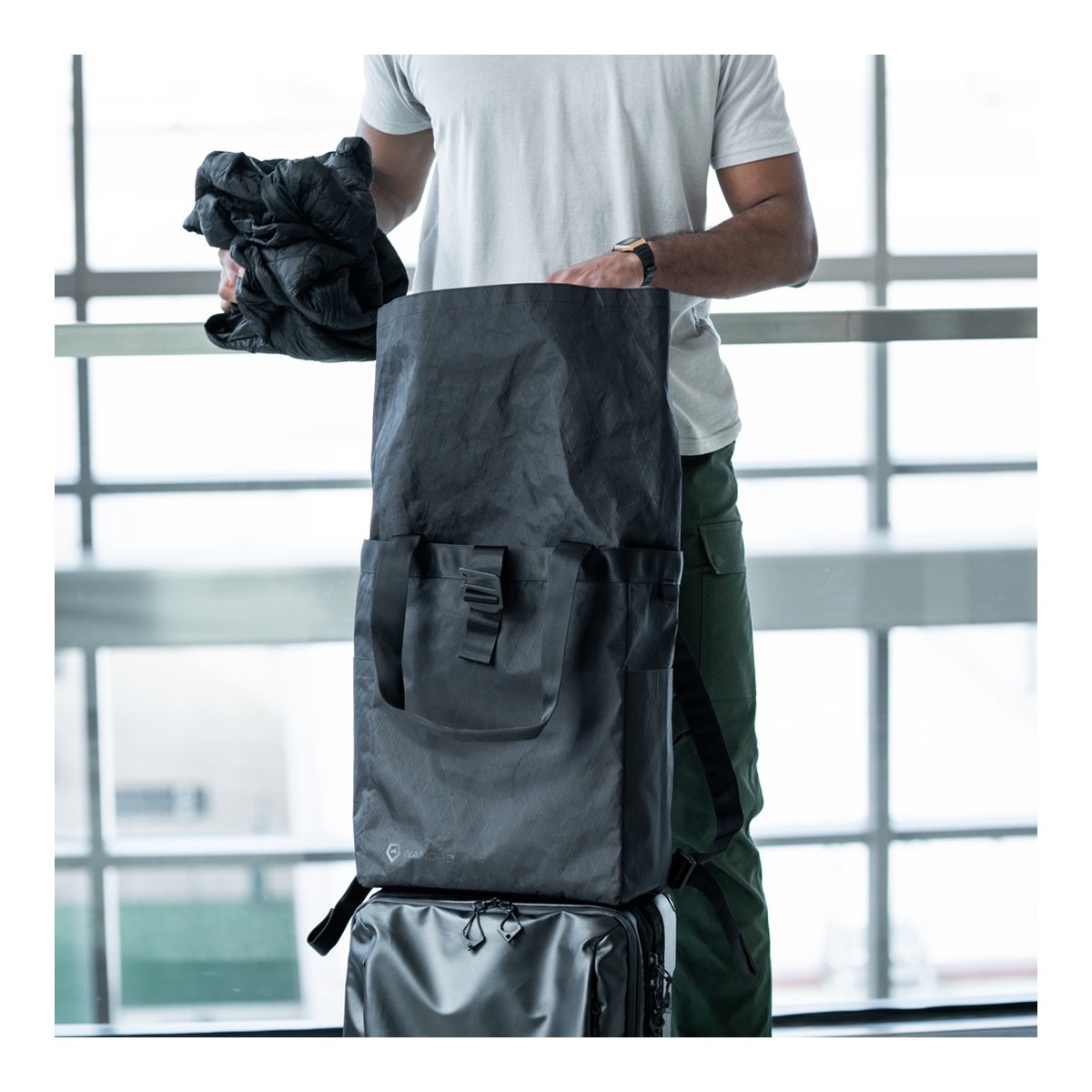 WANDRD Tote Backpack - Anwendungsbeispiel: Person packt schwarze Reisetasche WANDRD Tote Backpack - Anwendungsbeispiel: Person packt schwarze Reisetasche