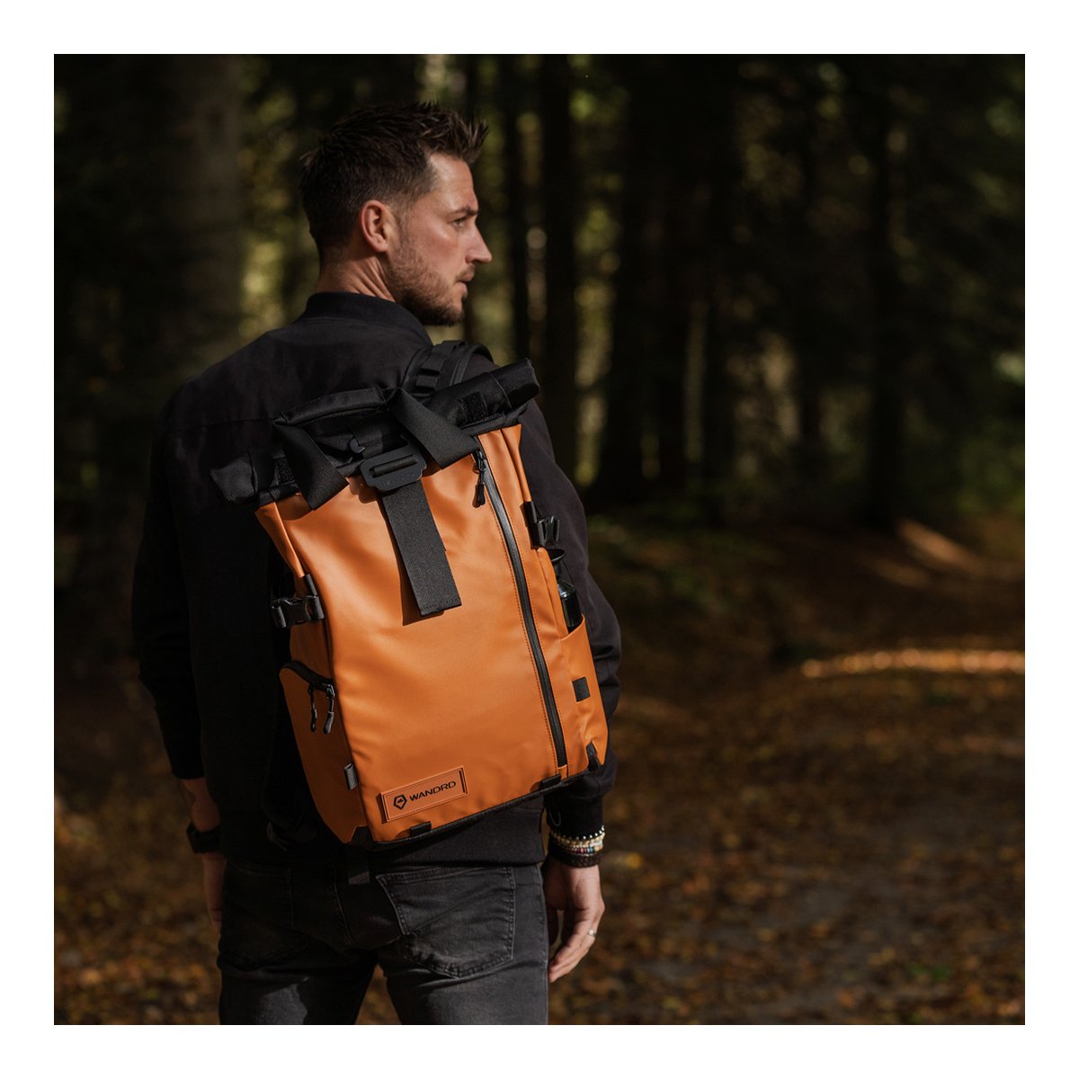 WANDRD PRVKE 21-Liter Sedona Orange Photo Bundle V3 - Anwendungsbeispiel am Rücken: Mann mit orange-schwarzem Roll-Top-Rucksack