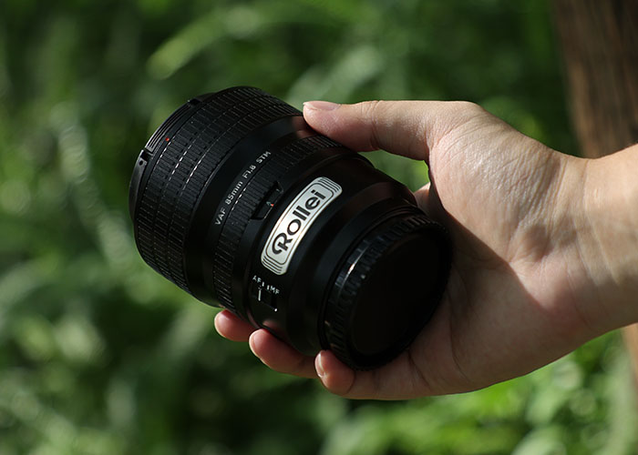 Rollei 85mm f1.8 Autofokus Objektiv in der Hand eines Fotografen im Freien