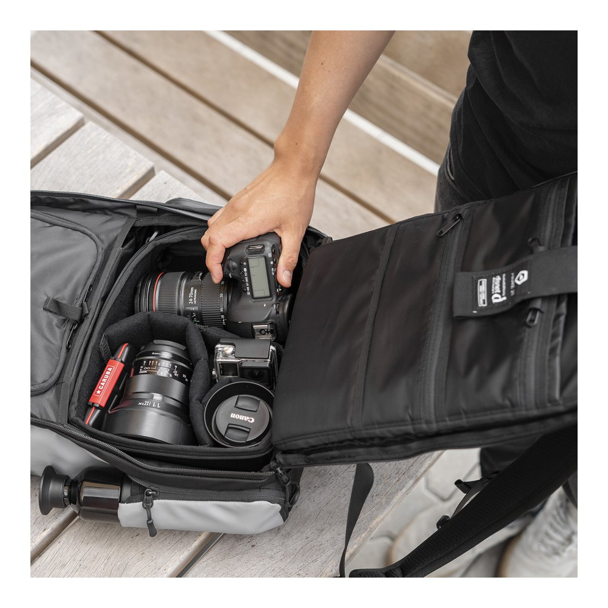 WANDRD PRVKE 21-Liter DisNet Grey Photo Bundel V3 - Anwendungsbeispiel: Geöffnete Kameratasche mit Hand, die eine DSLR herausnimmt, Objektive und Trinkflasche sind im Hauptfach. WANDRD PRVKE 21-Liter DisNet Grey Photo Bundel V3 - Anwendungsbeispiel: Geöffnete Kameratasche mit Hand, die eine DSLR herausnimmt, Objektive und Trinkflasche sind im Hauptfach.