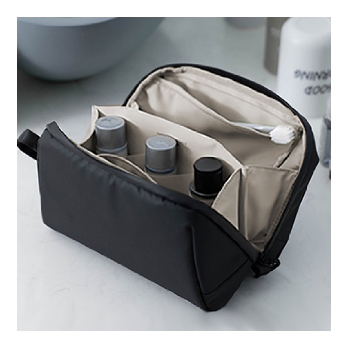 PGYTECH Wash Pouch(Twilight Black) - Anwendungsbeispiel: Geöffnete schwarze Kulturtasche mit Fächern, gefüllt mit Flaschen und Zahnbürste.
