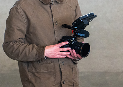 Panasonic S1II mit Rig und Mikrofon im Einsatz Filmemacher hält Panasonic Lumix S1II mit Rode-Mikrofon und Field Monitor