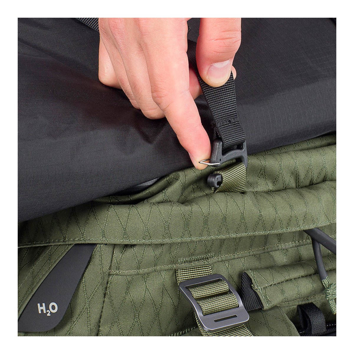 F-Stop - Gatekeeper Attachment Straps - Anwendungsbeispiel: Hand befestigt Ausrüstung am olivgrünen Rucksack-Gurtsystem, H₂O-Symbol für Trinksystem. F-Stop - Gatekeeper Attachment Straps - Anwendungsbeispiel: Hand befestigt Ausrüstung am olivgrünen Rucksack-Gurtsystem, H₂O-Symbol für Trinksystem.