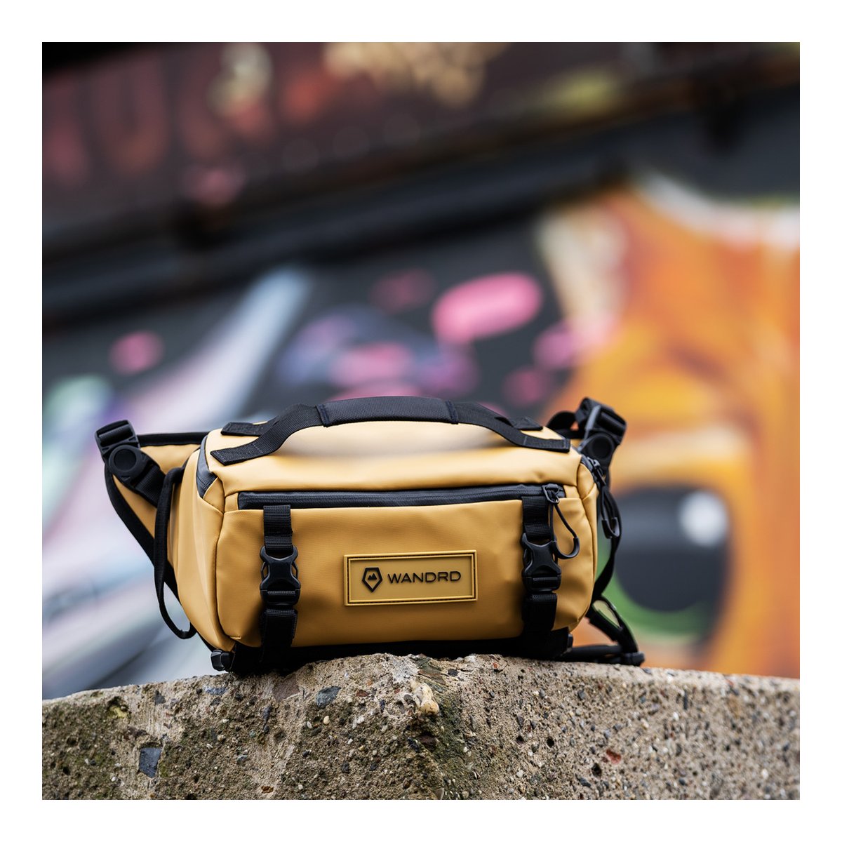 WANDRD ROGUE Sling 6L Dallol Yellow - Frontansicht der senfgelben WANDRD Tasche auf rauem Beton