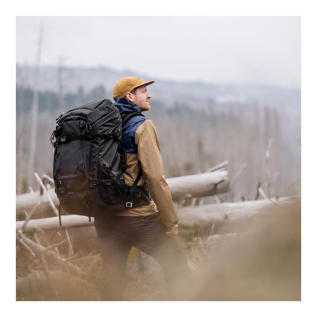 F-Stop DuraDiamond Shinn - Anthrazit - Anwendungsbeispiel: Mann trägt schwarzen Wanderrucksack beim Trekking in bewaldeter Landschaft.