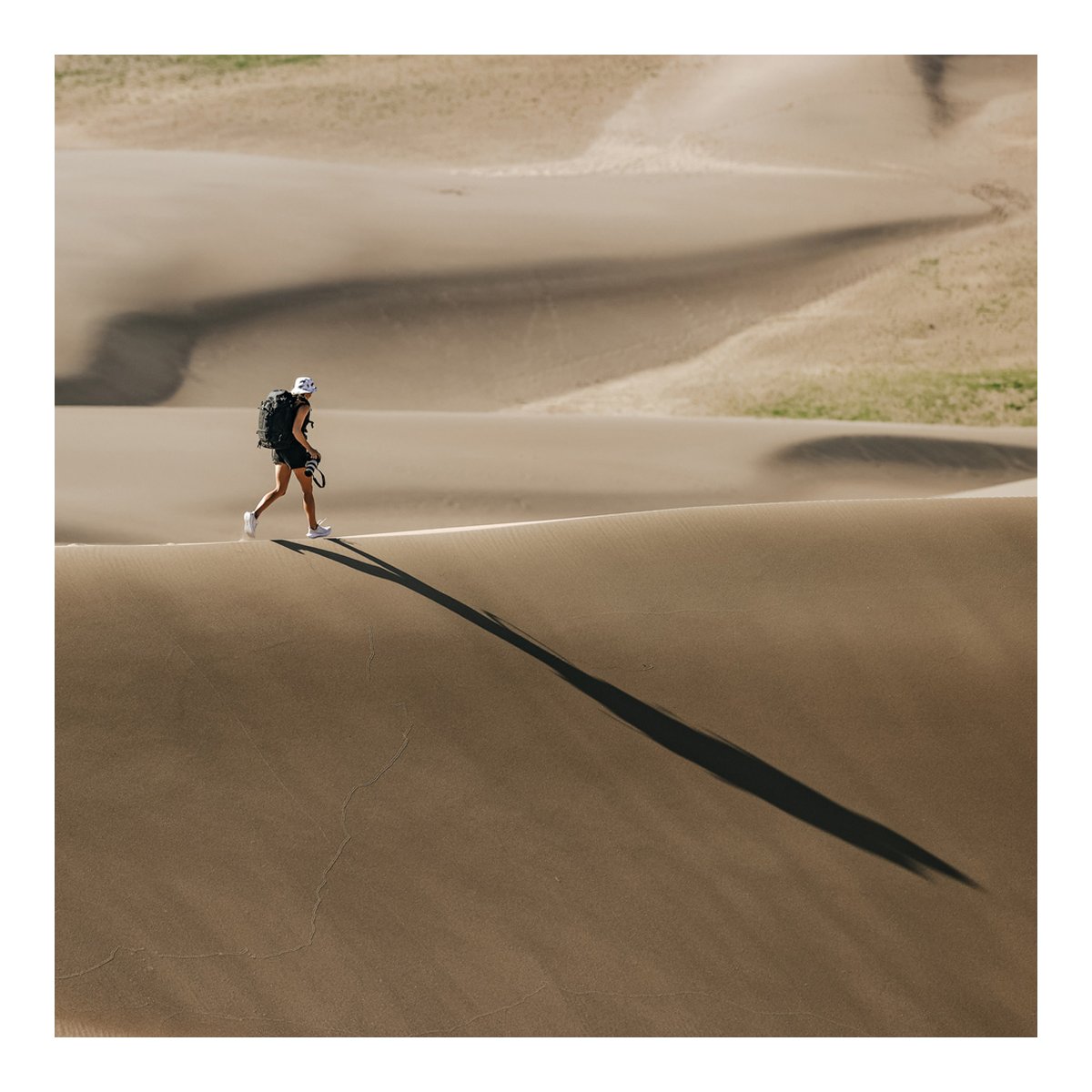 F-Stop DuraDiamond Shinn - Anthrazit - Anwendungsbeispiel: Person mit Rucksack wandert auf Sanddüne, langer Schatten im Sand. F-Stop DuraDiamond Shinn - Anthrazit - Anwendungsbeispiel: Person mit Rucksack wandert auf Sanddüne, langer Schatten im Sand.