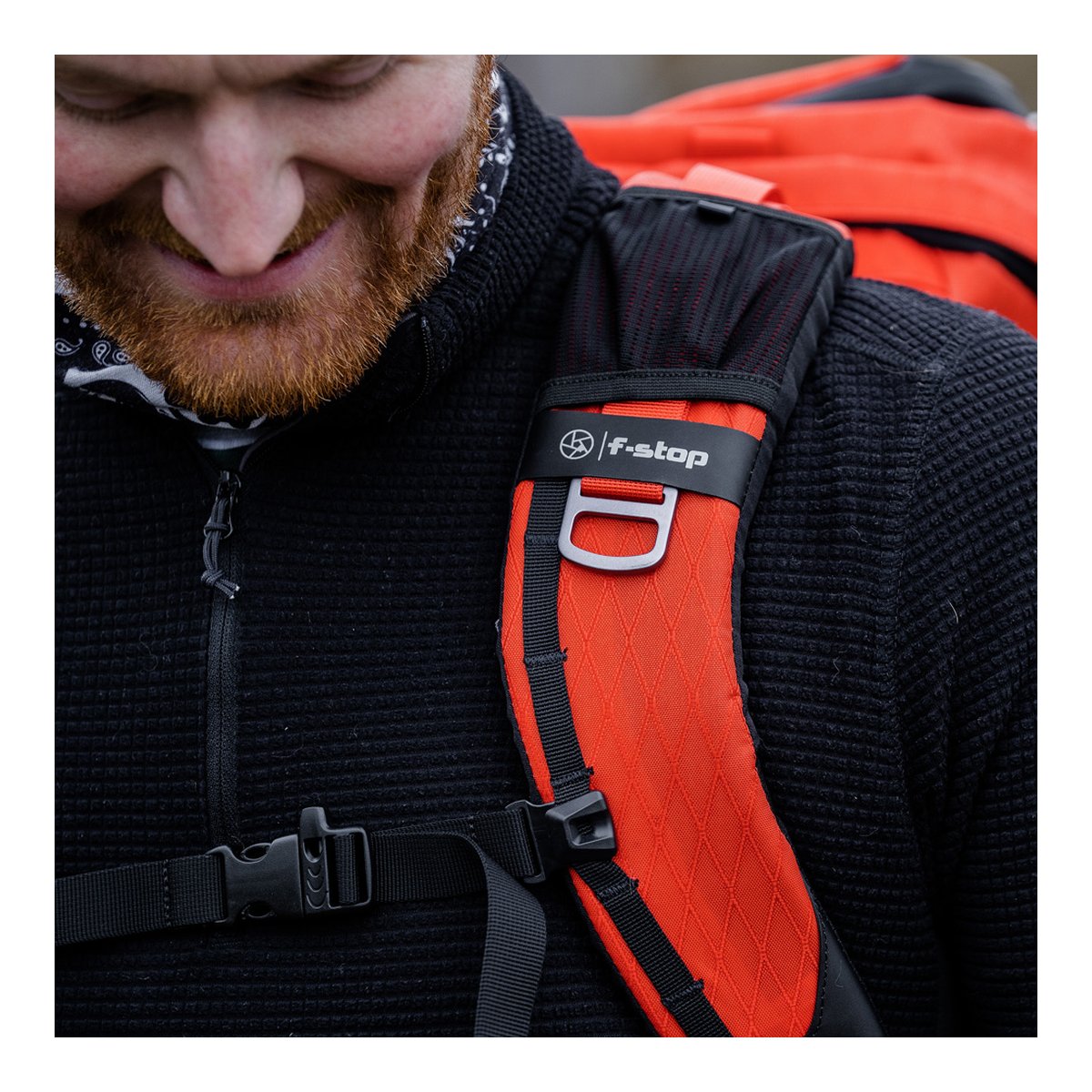 F-Stop DuraDiamond Tilopa Bundle - Magma - ANWENDUNGSBEISPIEL: DETAILANSICHT DES ORANGEN SCHULTERGURTS MIT F-STOP LOGO, D-RING UND BRUSTGURT AM TRÄGER.