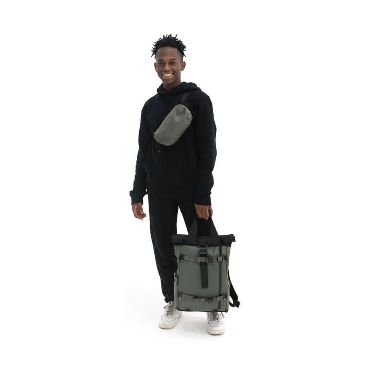 WANDRD PREMIUM ACCESSORY STRAP WASATCH GREEN V2 - Anwendungsbeispiel: Mann hält Tasche und trägt Bauchtasche quer.