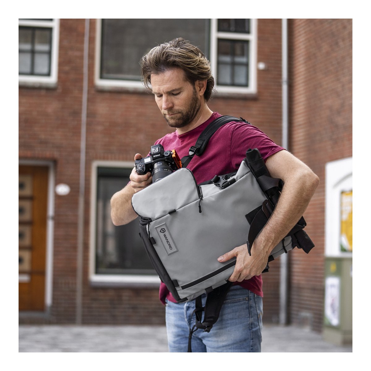 WANDRD PRVKE 31-Liter DisNet Grey Photo Bundle - Anwendungsbeispiel: Mann mit Kamera und grauer Kameratasche.