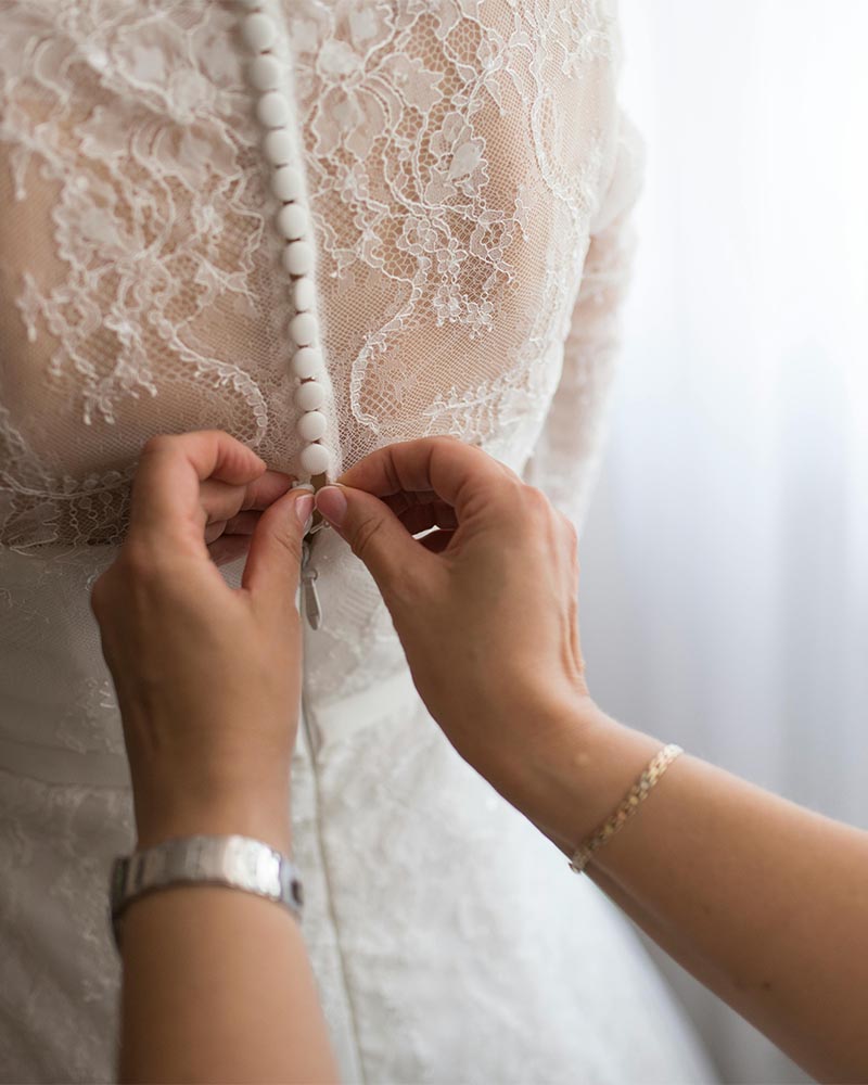 Getting Ready – Knöpfe am Brautkleid schließen Hände beim Schließen des Brautkleids – emotionaler Moment beim Getting Ready am Hochzeitstag