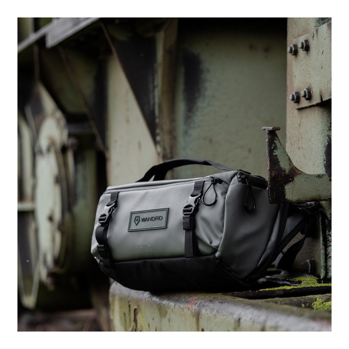 WANDRD ROGUE Sling 9L Wasatch Green - Anwendungsbeispiel: Graue WANDRD Tasche mit Wassertropfen auf rostigem Metall.