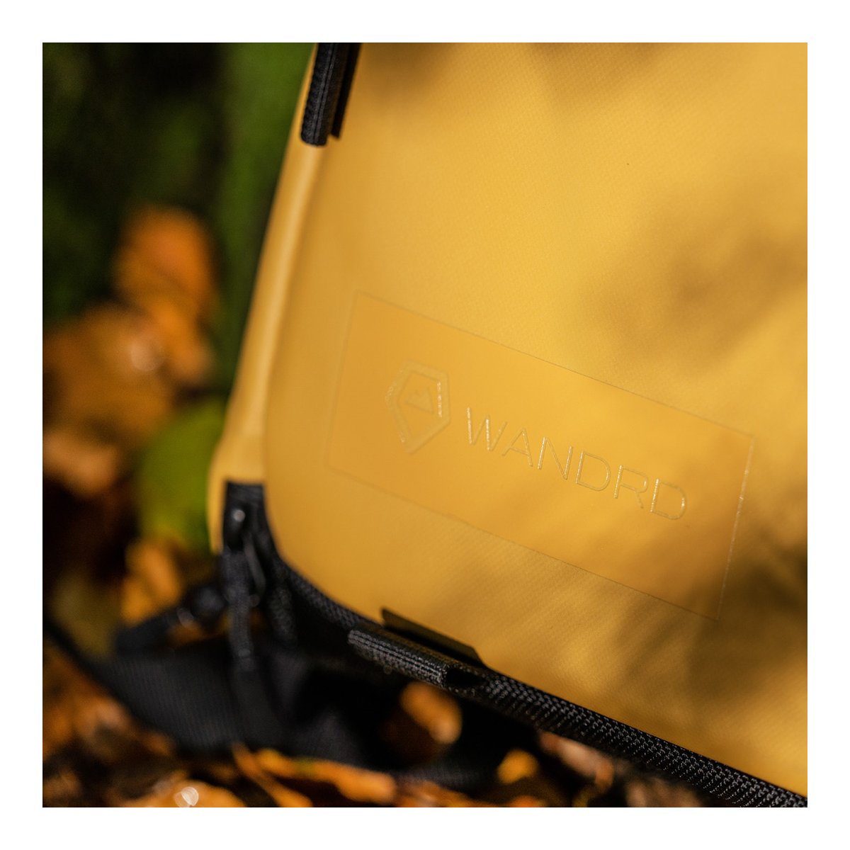 WANDRD PRVKE Lite 11-Liter Dallol Yellow - Detailansicht: Eingeprägtes WANDRD-Logo auf gelbem Material.