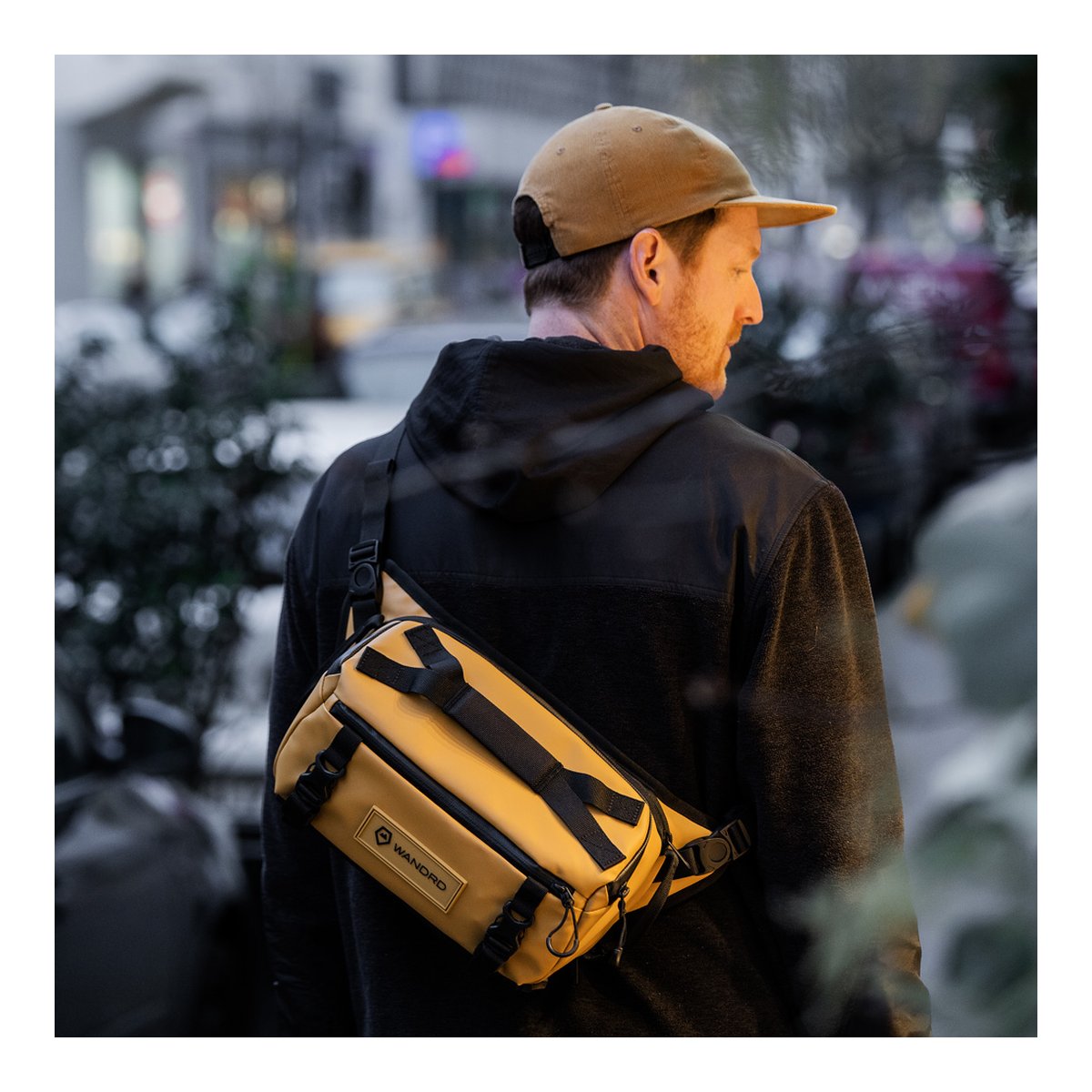 WANDRD ROGUE Sling 6L Dallol Yellow - Anwendungsbeispiel: Mann trägt gelbbraune Sling Bag quer auf dem Rücken.