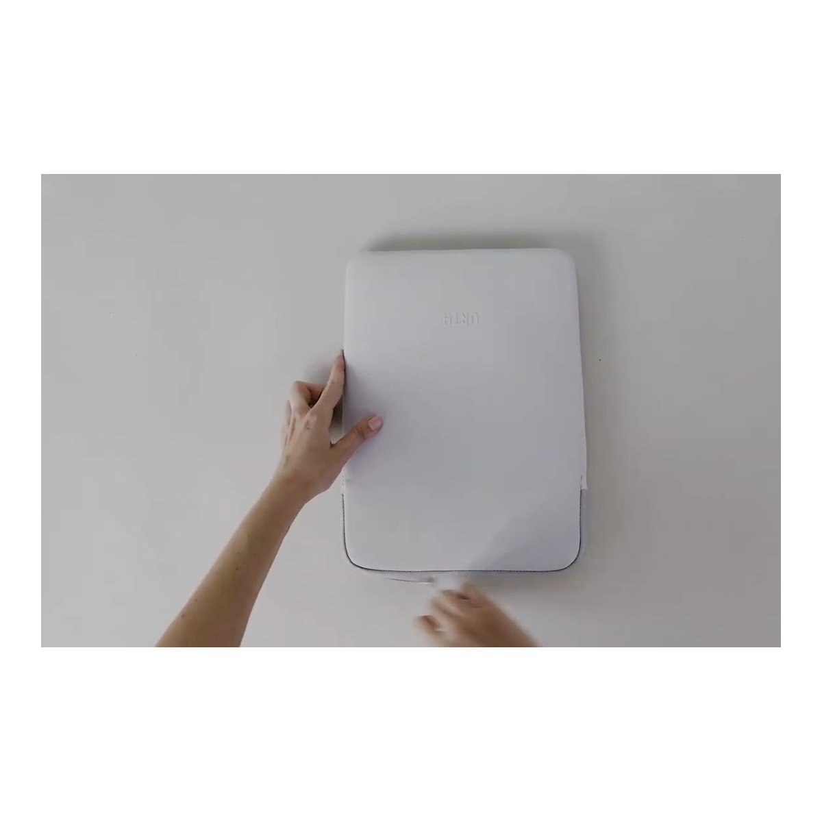 Urth Naos 15/16" Laptoptasche (Aschgrau) - Montagebeispiel: Hände befestigen weißes Wandgerät.