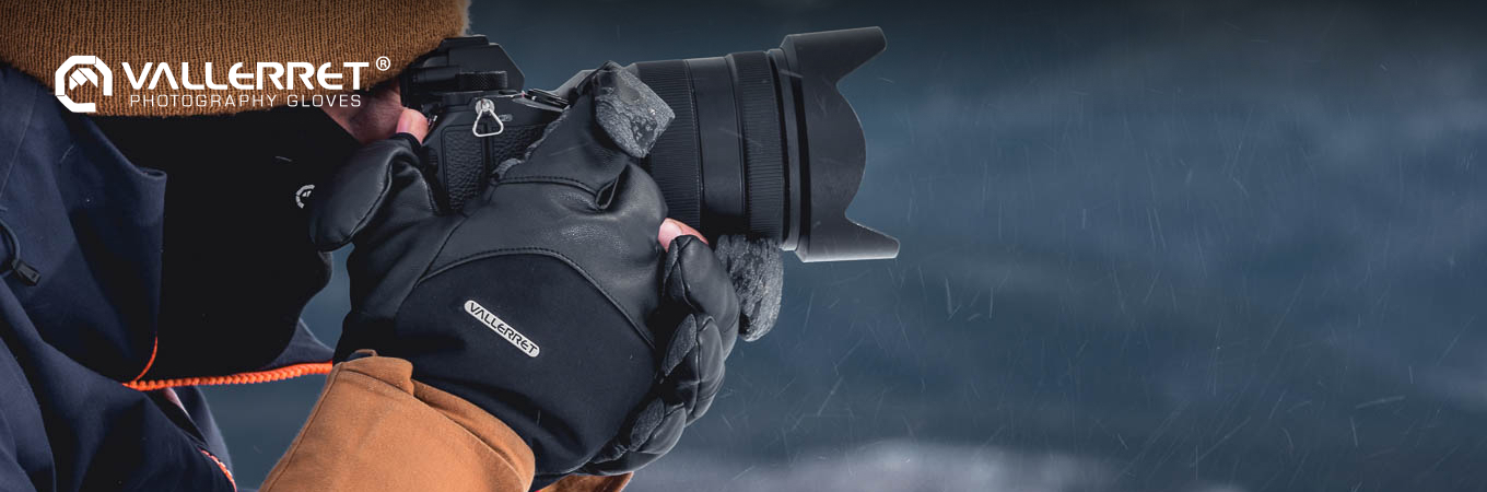 Fotograf mit Kamera im verschneiten Winterwald trägt Vallerret Fotohandschuhe und bedient Objektivring und Auslöser