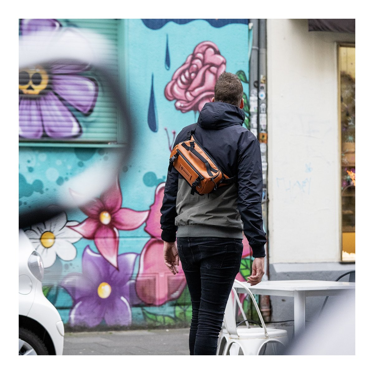 WANDRD ROGUE Sling 6L Sedona Orange - Anwendungsbeispiel: Rückansicht der braunen Tasche auf dem Rücken eines Mannes.