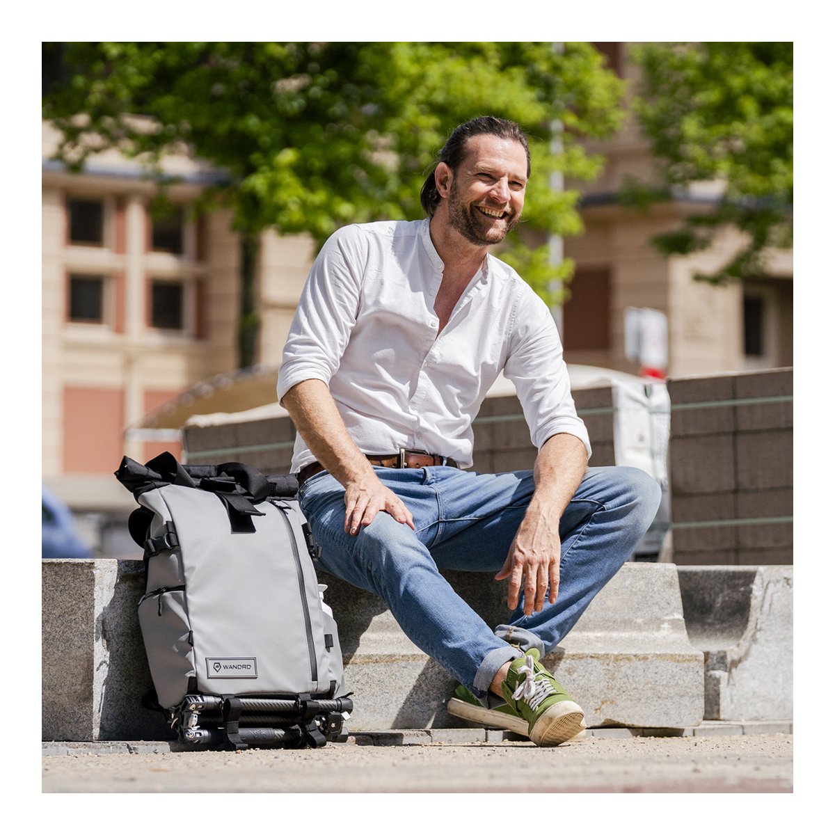 WANDRD PRVKE 31-Liter DisNet Grey Photo Bundle - Anwendungsbeispiel: Grau-schwarzer Wandrd Rucksack neben lachendem Mann auf Treppe.