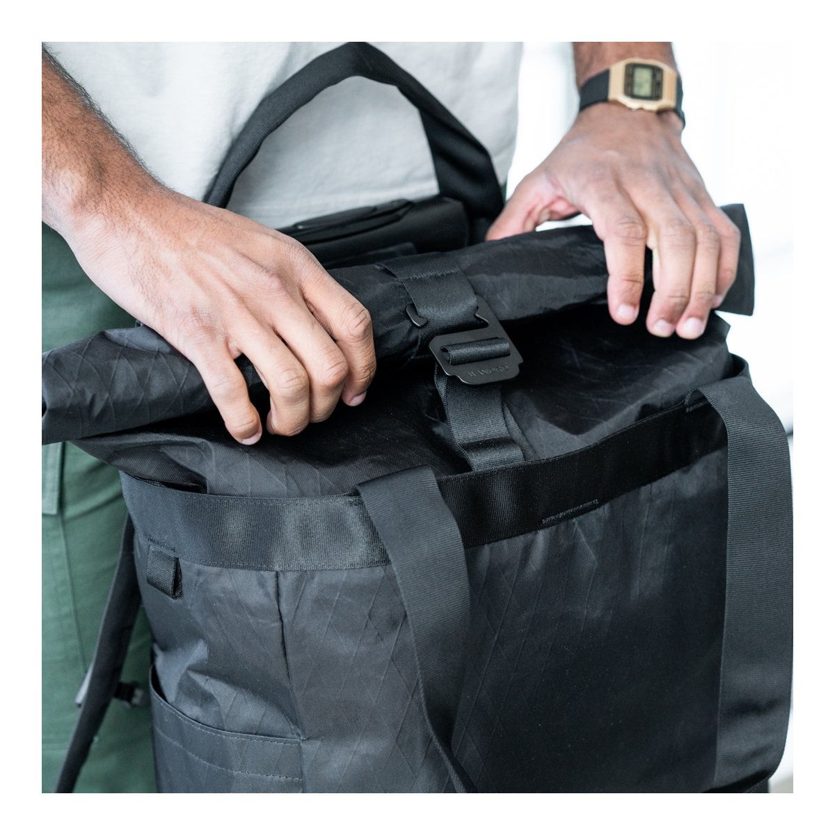 WANDRD Tote Backpack - Anwendungsbeispiel: Hände schließen Rolltop-Tasche. WANDRD Tote Backpack - Anwendungsbeispiel: Hände schließen Rolltop-Tasche.