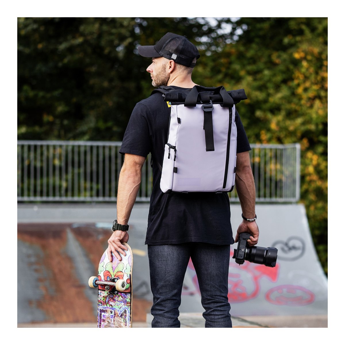 WANDRD PRVKE Lite 11-Liter Uyuni Purple - Anwendungsbeispiel: Mann mit hellgrauem Roll-Top-Rucksack, Skateboard und Kamera im Skatepark. WANDRD PRVKE Lite 11-Liter Uyuni Purple - Anwendungsbeispiel: Mann mit hellgrauem Roll-Top-Rucksack, Skateboard und Kamera im Skatepark.