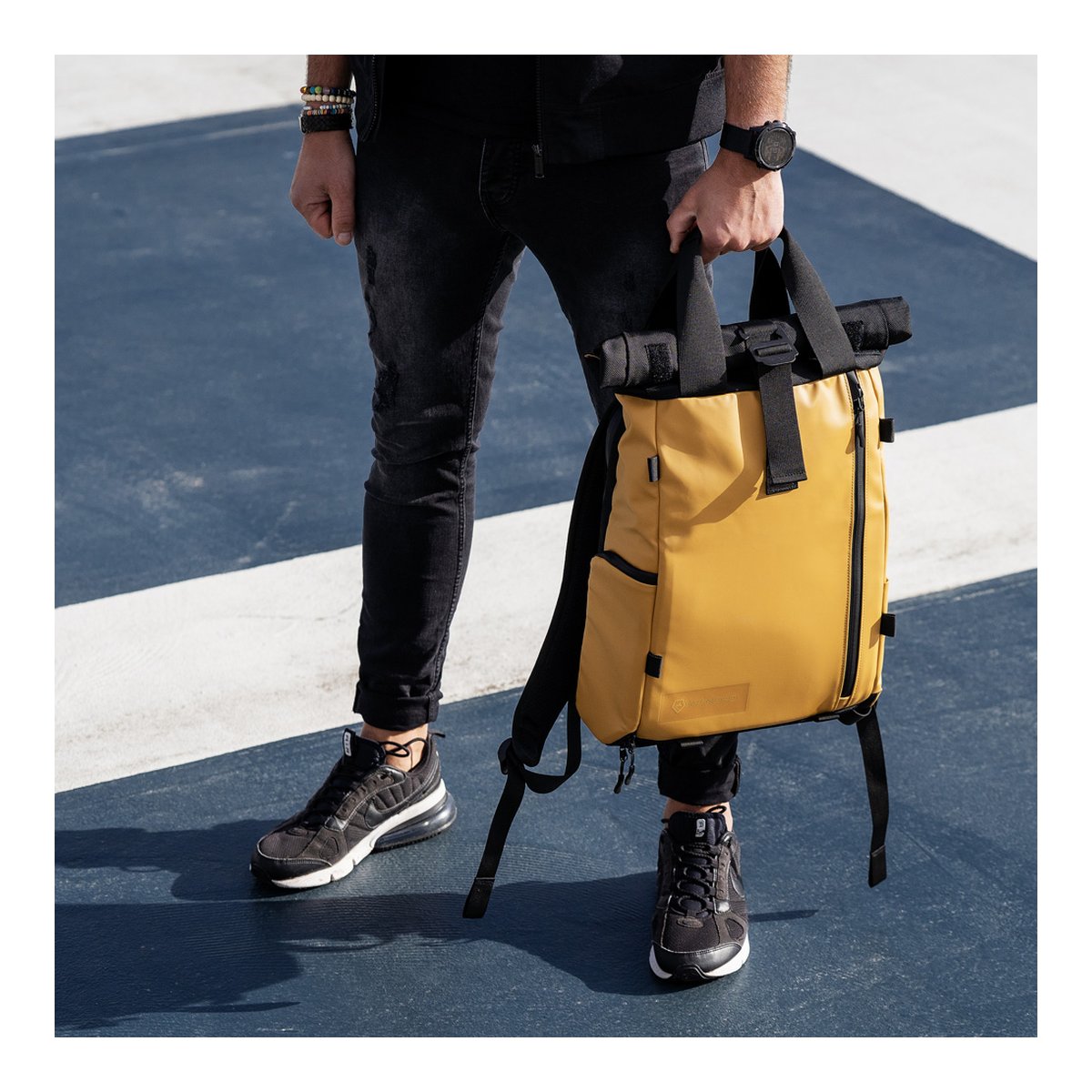 WANDRD PRVKE Lite 11-Liter Dallol Yellow - Anwendungsbeispiel: Person trägt senfgelben Rucksack am oberen Griff.