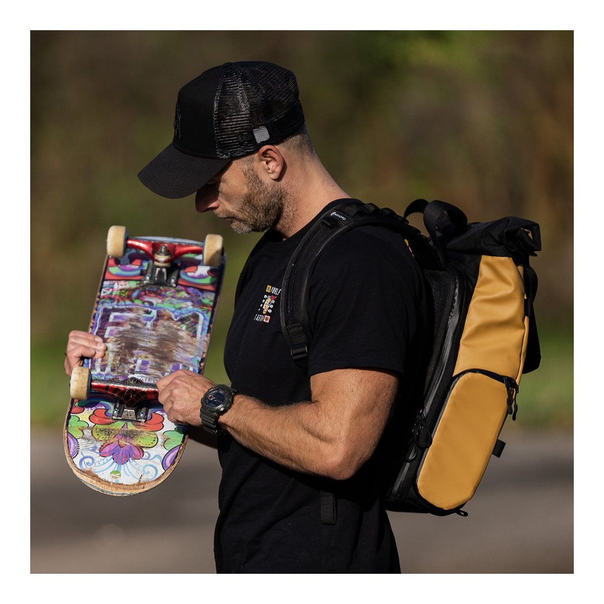 WANDRD PRVKE Lite 11-Liter Dallol Yellow - Anwendungsbeispiel: Mann trägt Rucksack und hält Skateboard, Seitenansicht