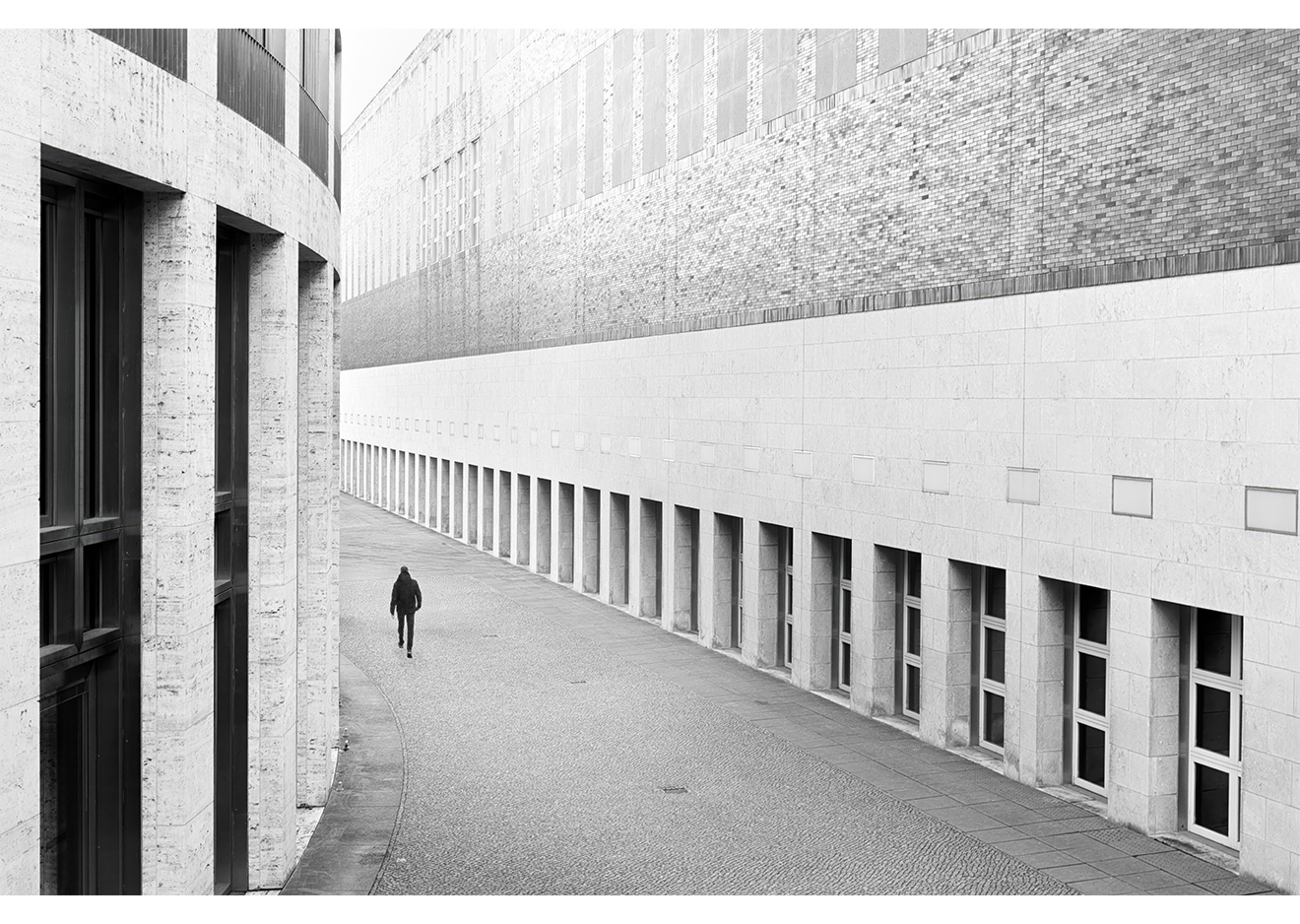 Schwarzweiß-Fotografie moderner Architektur mit Person in der Bildmitte – aufgenommen mit Fujifilm GFX100RF