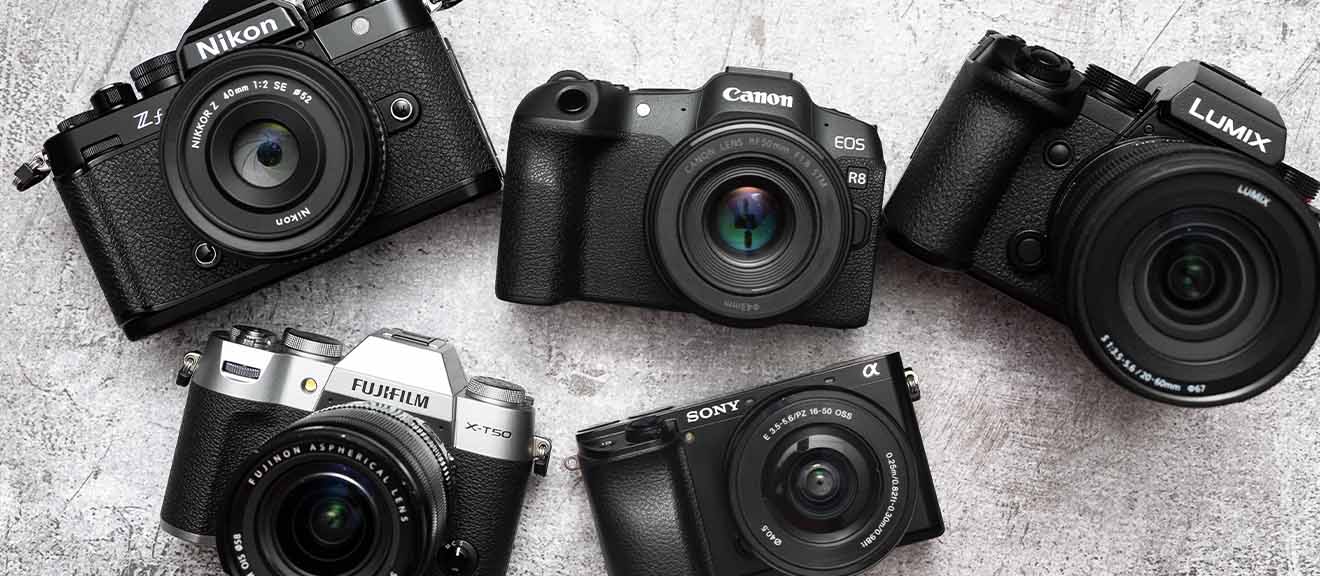 Verschiedene Kameramodelle auf hellem Hintergrund: Nikon Zf, Canon EOS R8, Fujifilm X-T50, Sony Alpha 6700 und Panasonic Lumix. Kameras für unterschiedliche Einsatzzwecke wie Porträtfotografie, Landschaftsfotografie und Videografie.
