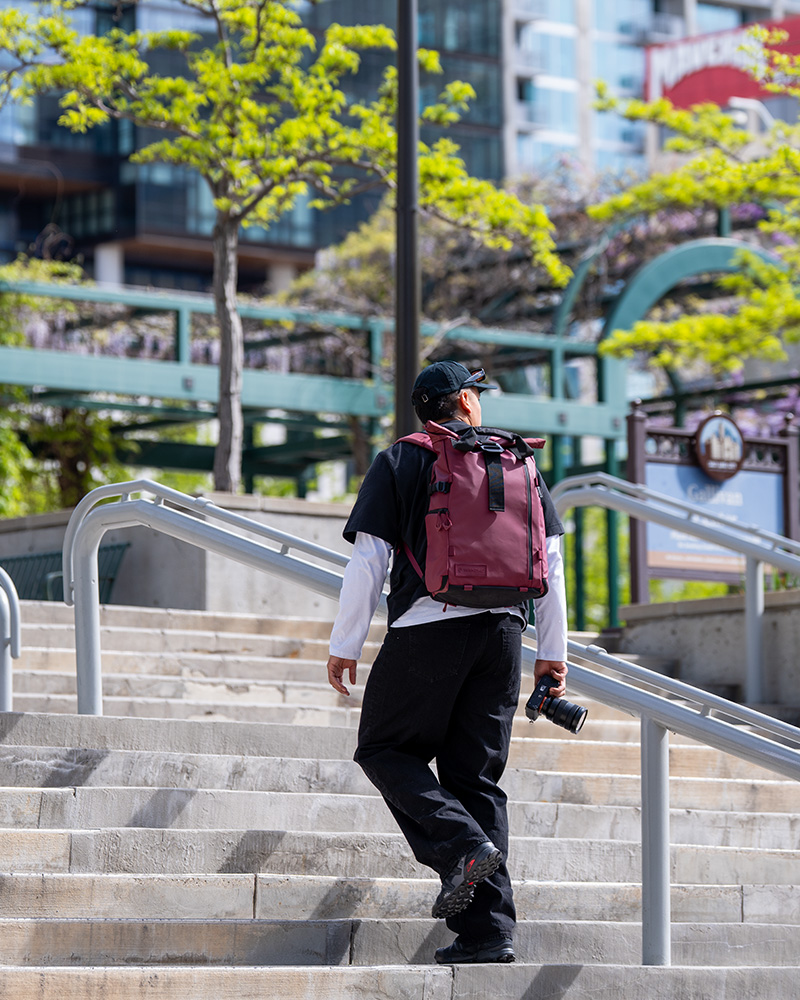 Mann mit rotem Wandrd PRVKE V4 Rucksack beim Fotografieren in der Stadt
