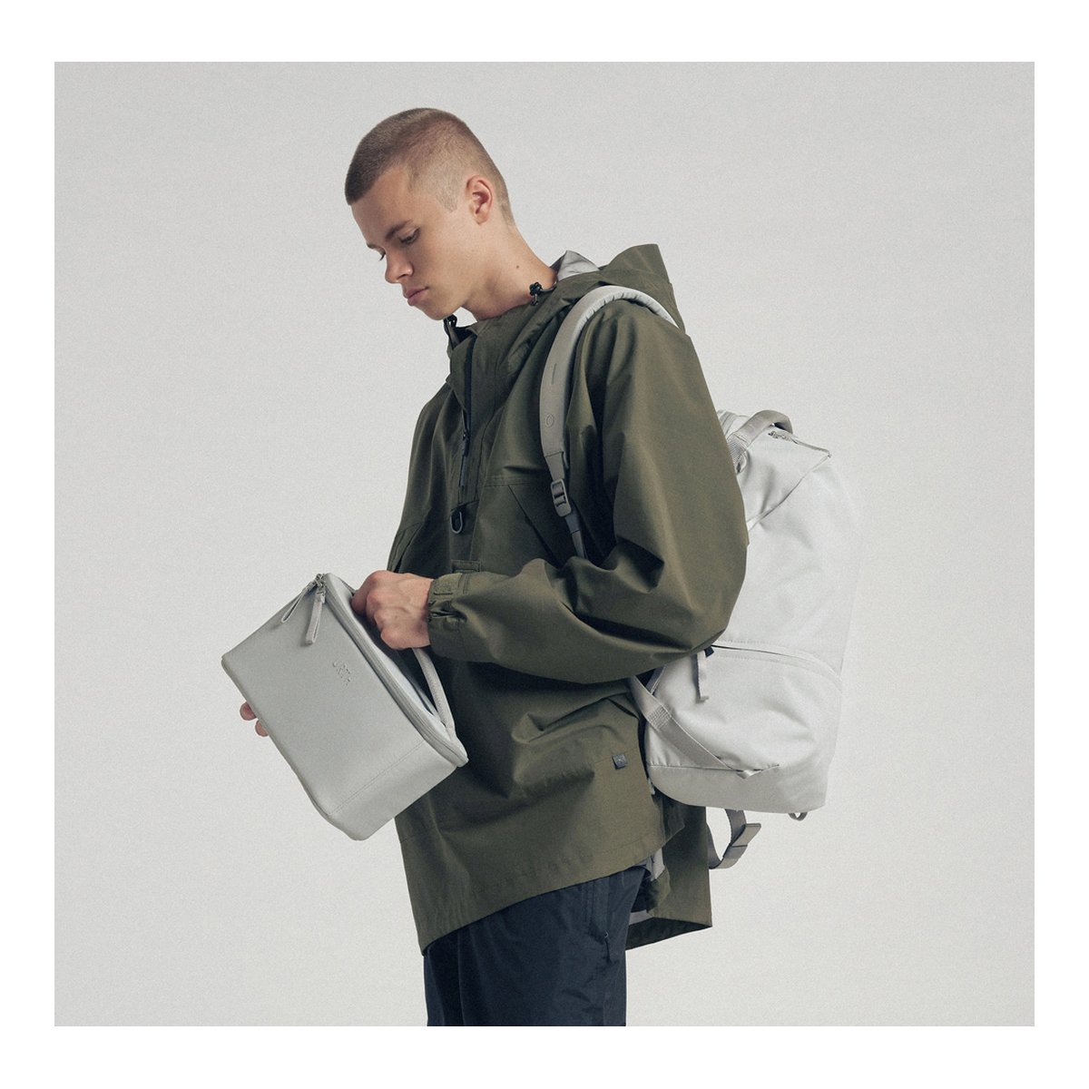 Urth Arkose 20L Rucksack + Kamera Insert (Aschgrau) - Anwendungsbeispiel: Mann mit Rucksack öffnet separate Tasche.