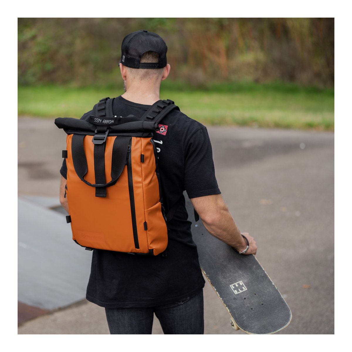 WANDRD PRVKE Lite 11-Liter Sedona Orange - Anwendungsbeispiel: Orangefarbener Roll-Top-Rucksack am Rücken einer Person mit Skateboard.