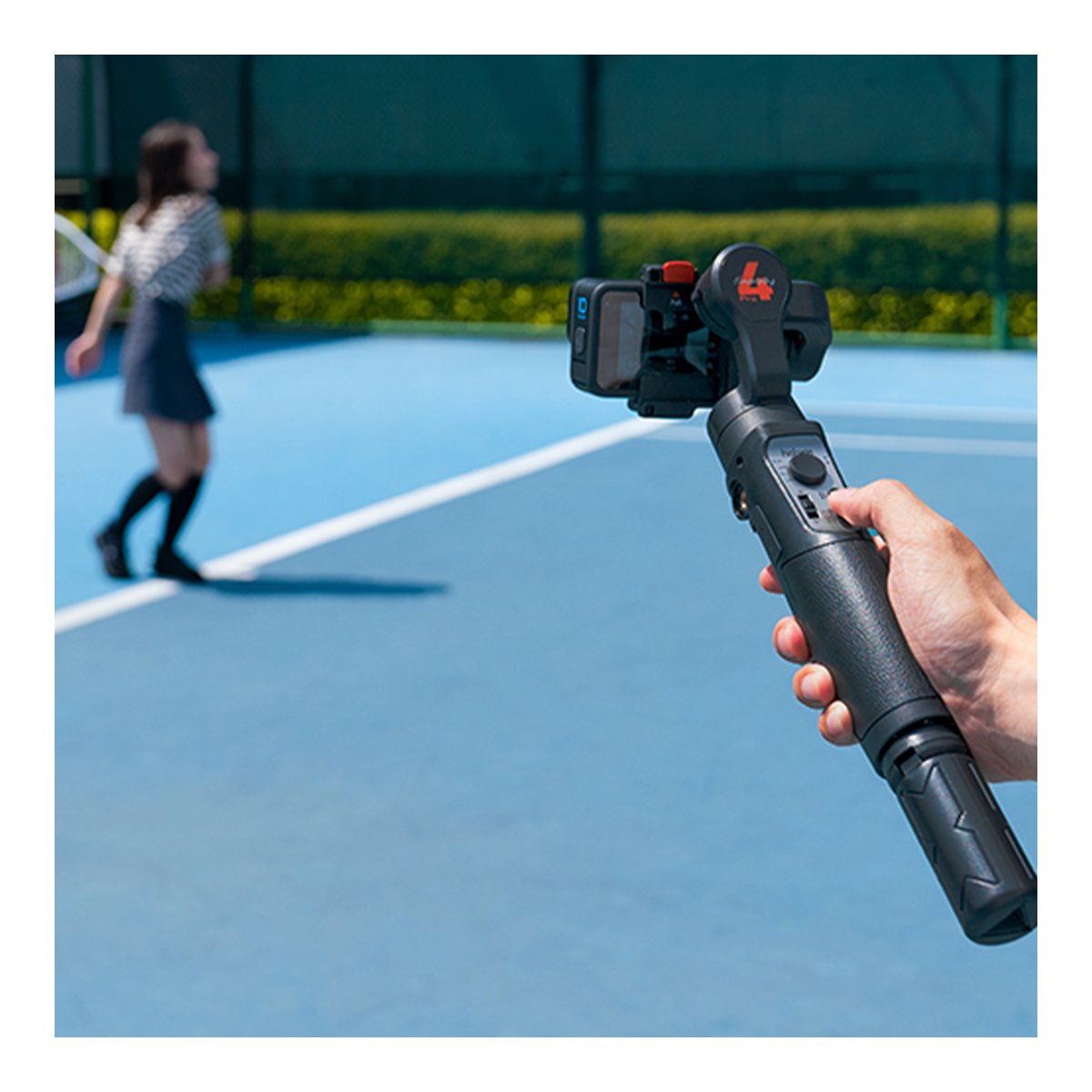 Hohem iSteady Pro4 - Anwendungsbeispiel auf Sportplatz: Hand hält Gimbal mit Action-Kamera.