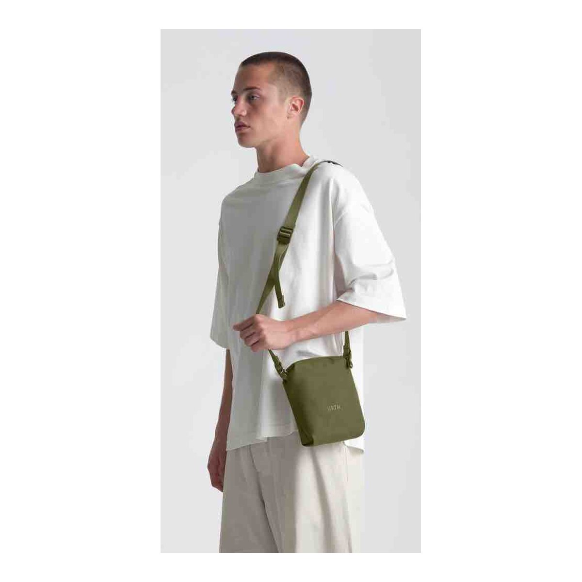 Urth Andesite Camera Pouch (Green) - Tragebeispiel: Olivgrüne Crossbody-Tasche an jungem Mann. Urth Andesite Camera Pouch (Green) - Tragebeispiel: Olivgrüne Crossbody-Tasche an jungem Mann.