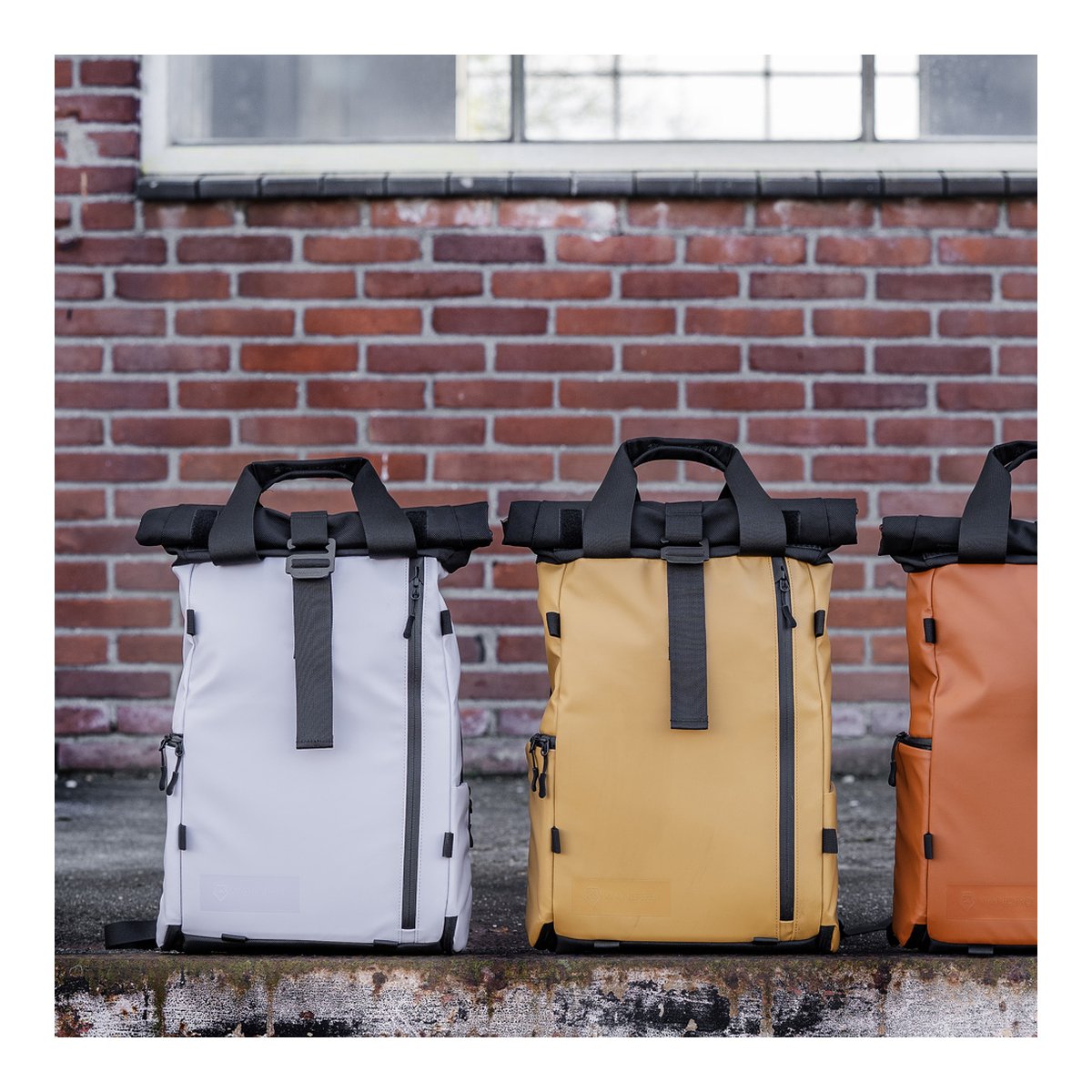 WANDRD PRVKE Lite 11-Liter Uyuni Purple - Produktsortiment: Drei Roll-Top-Rucksäcke in Weiß, Gelb und Orange nebeneinander.