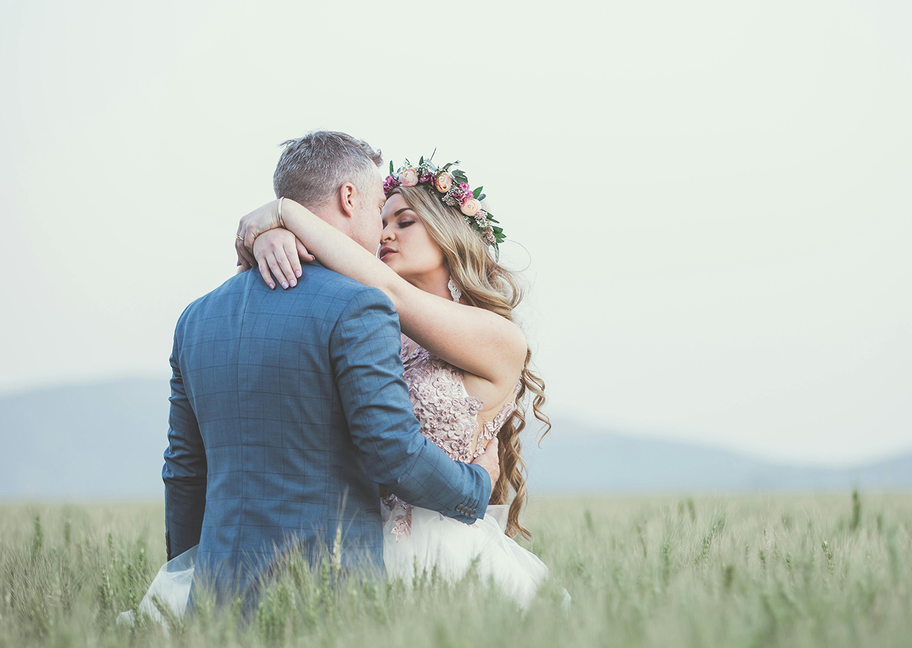 Romantischer Kuss im Feld – Brautpaar im natürlichen Setting Brautpaar beim innigen Kuss in einem Feld – natürliches und emotionales Hochzeitsfoto