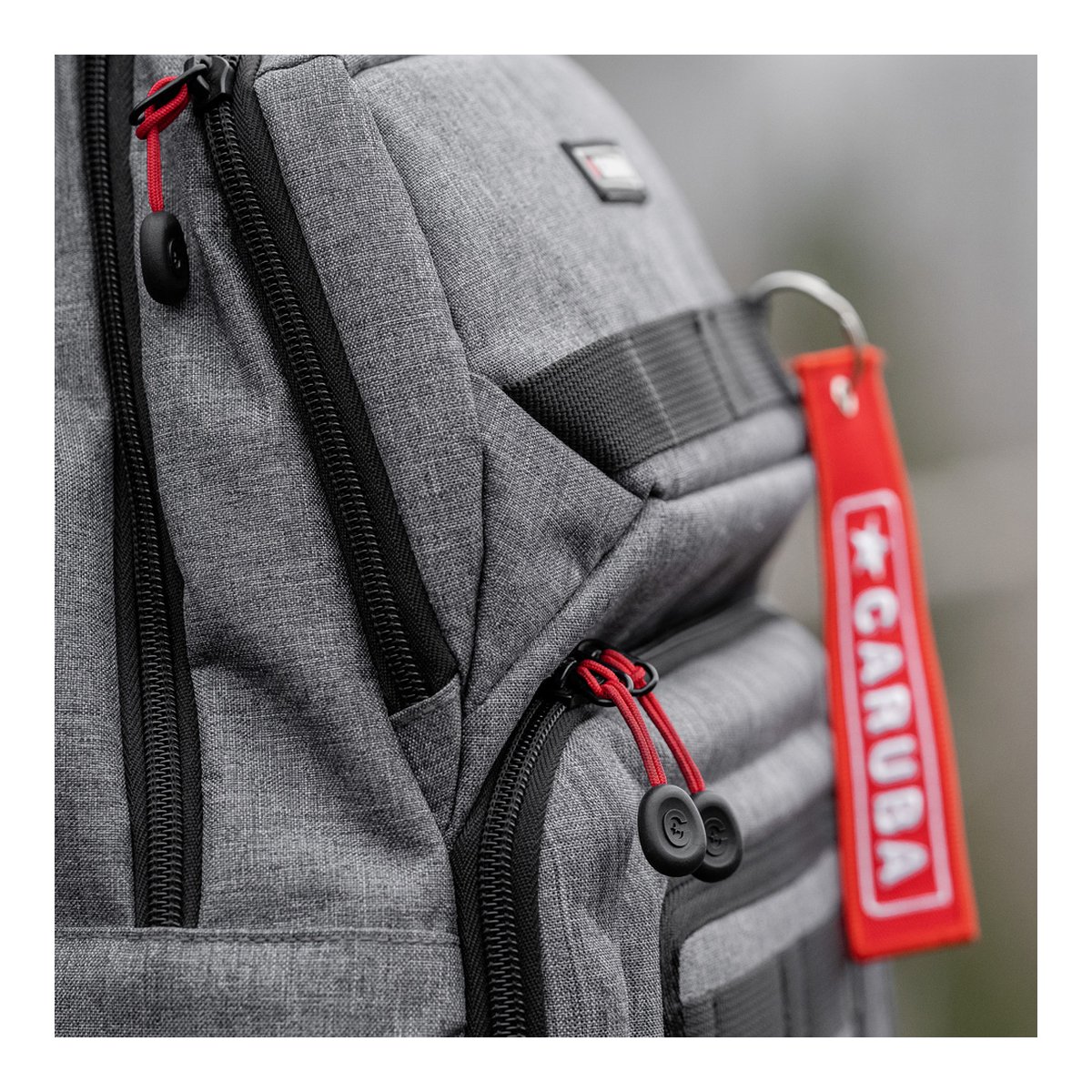 Caruba Skyline 100 Drohnenpack Grau - Detailansicht Reißverschlüsse und CARUBA-Anhänger am grauen Rucksack